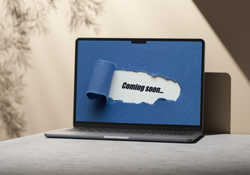 Image of a laptop on a table with a screen that says Coming Soon